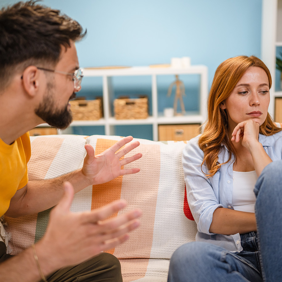 Ein Paar sitzt auf der Couch und diskutiert. 