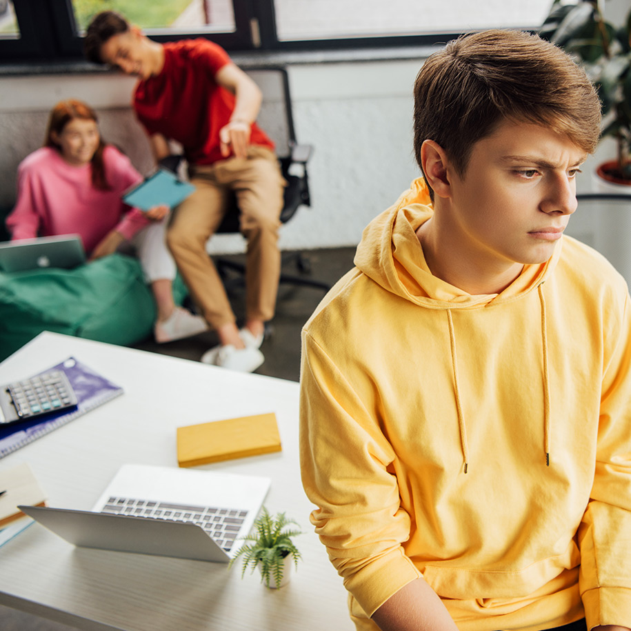 Ein Teenager sitzt ausgeschlossen im Bildvordergrund.