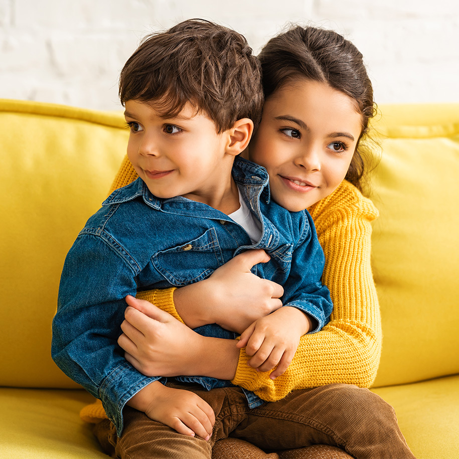 Eltern üben mit ihrem Sohn Gitarre auf der Couch.