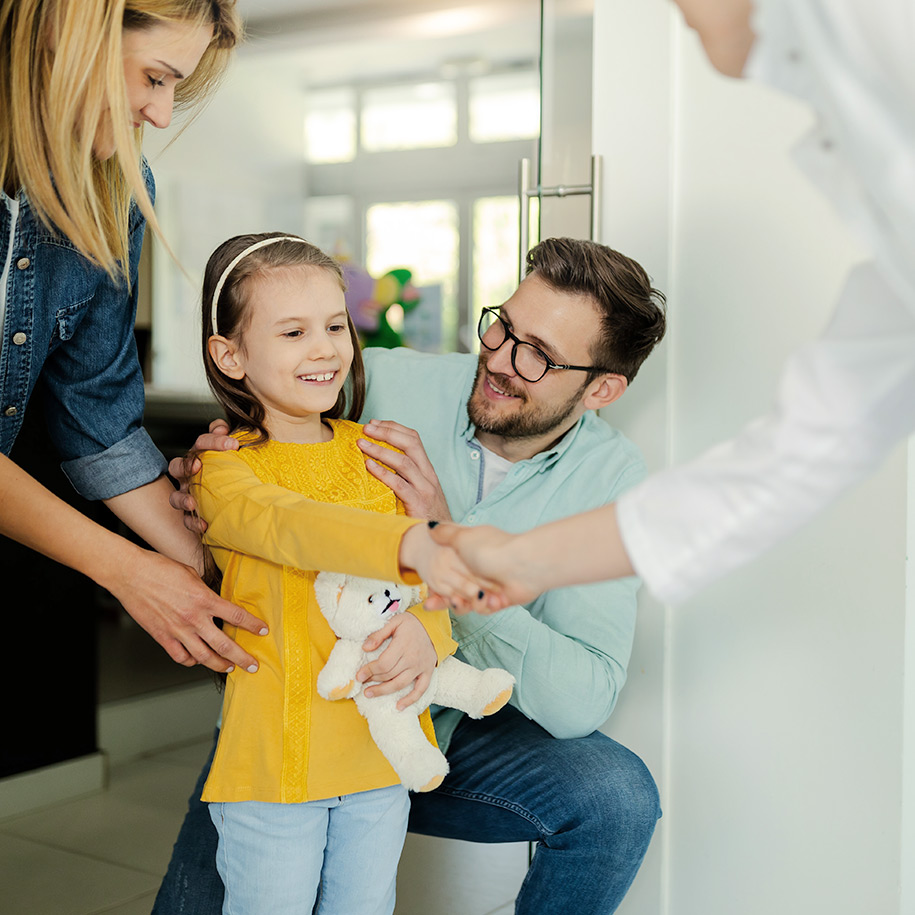 Ein kleines Mädchen mit einem Kuscheltier schüttelt die Hand eines Arztes.