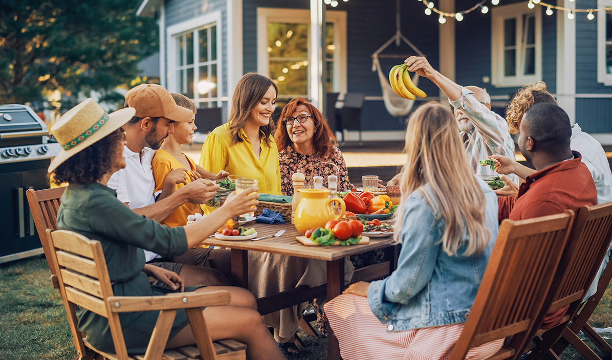Eine Gruppe Personen sitzt im Garten am Tisch.